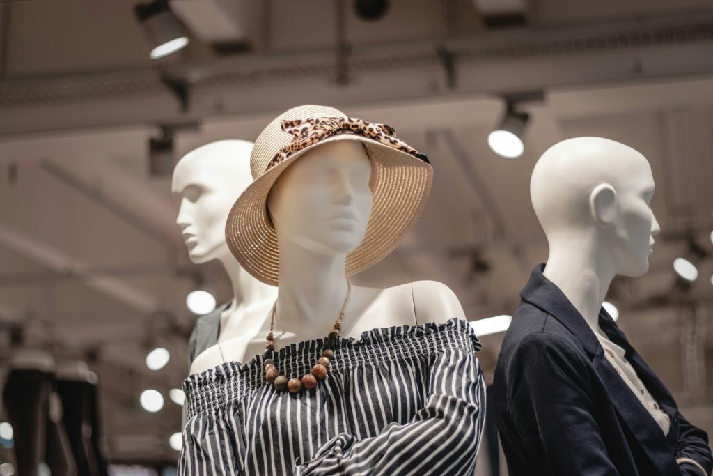 Maniquíes con ropa de moda, uno con sombrero y vestido a rayas, en exhibición dentro de un centro comercial