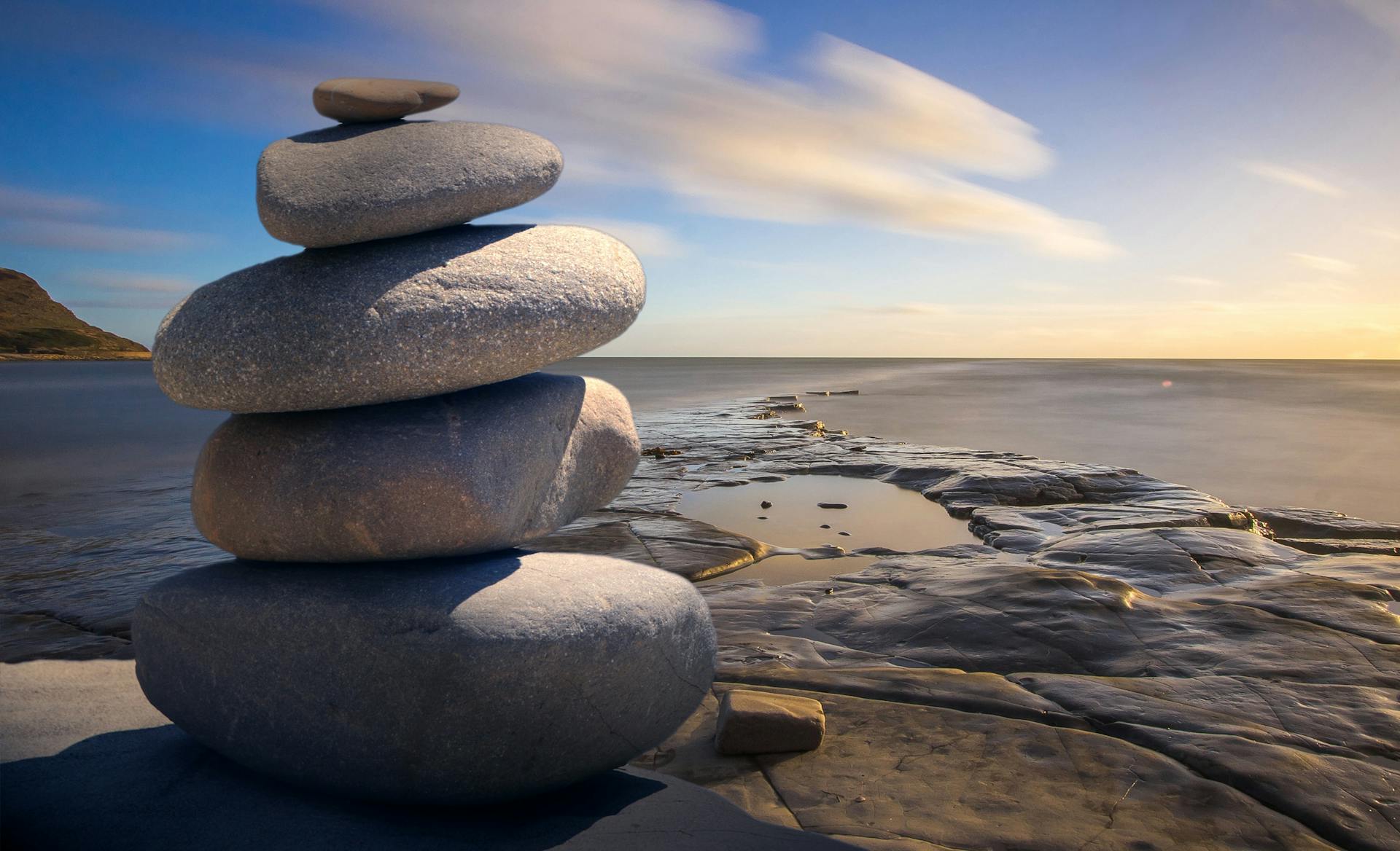 Hotel wellness Punta Cana: piedras apiladas estilo zen frente al mar al atardecer, símbolo de bienestar, calma y equilibrio.